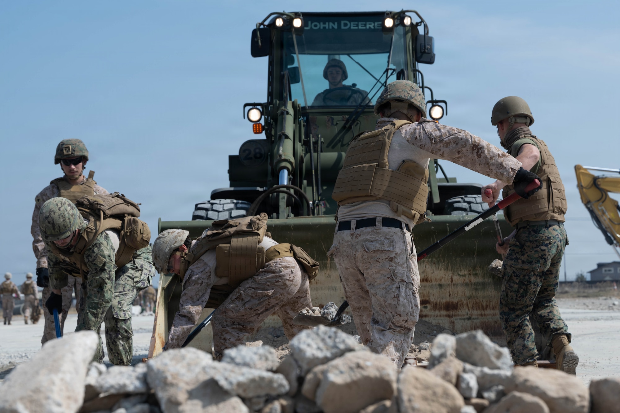 Service members move rocks.