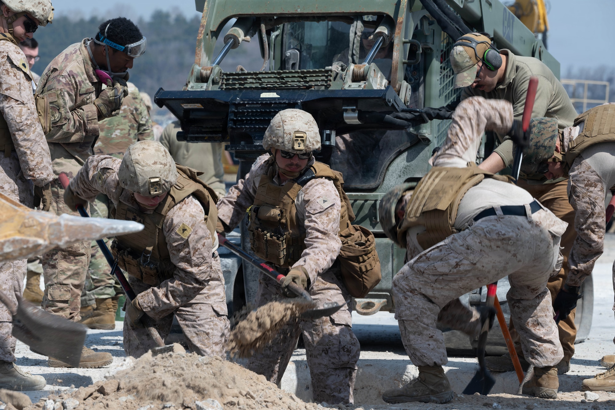 Service members dig a crater.