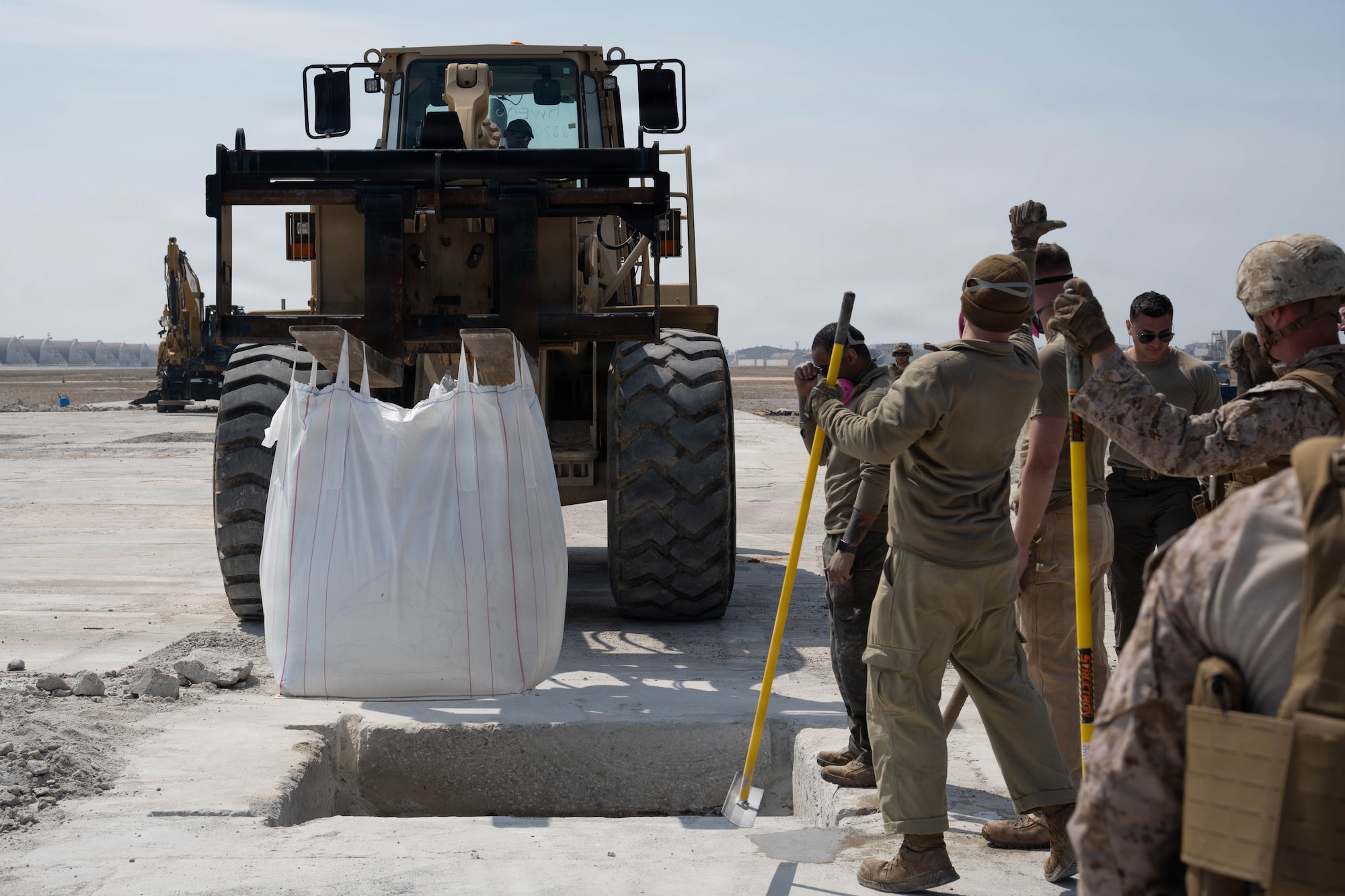 Service members guide a forklift.