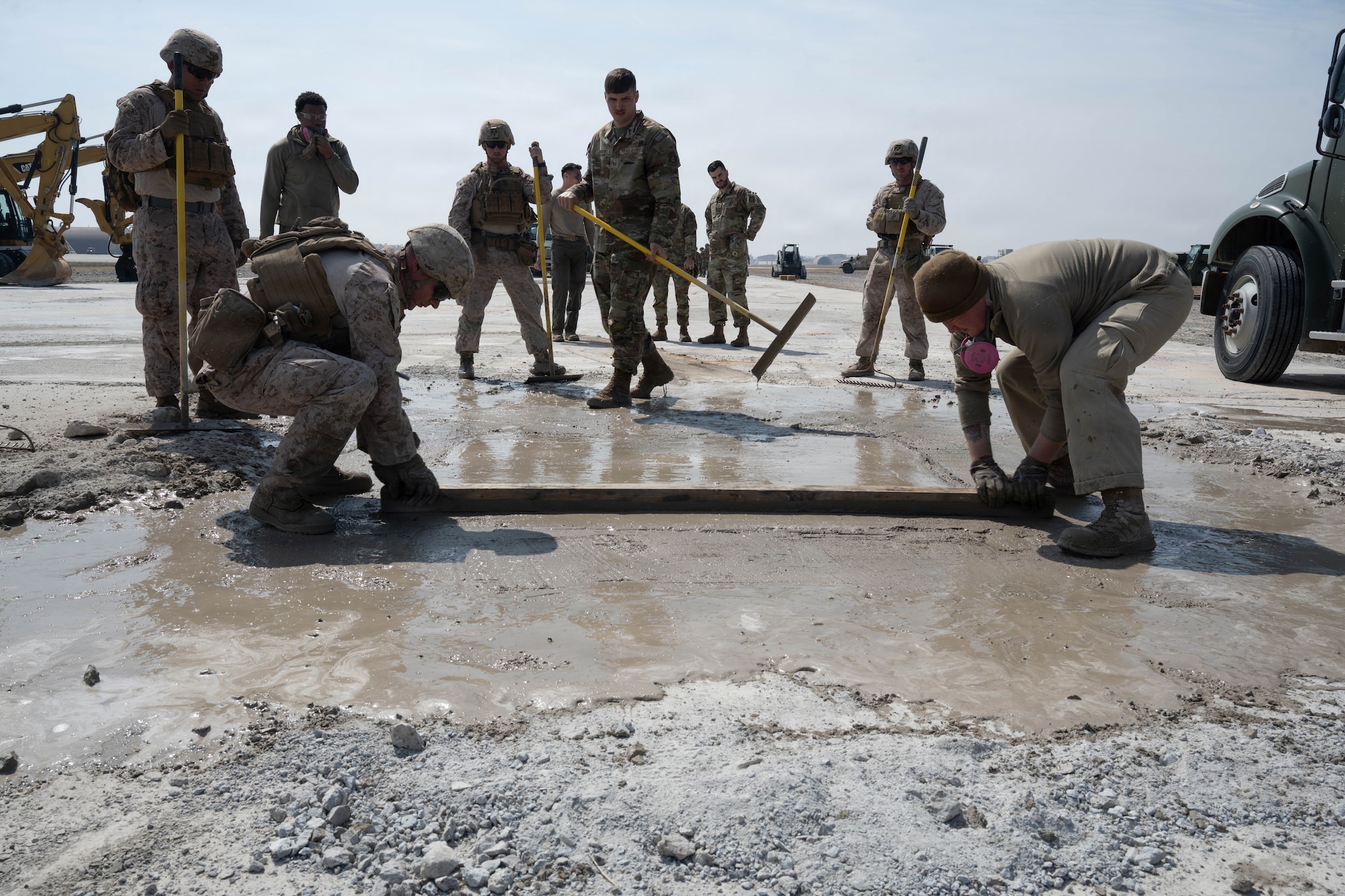 Marine and Airman smooth out concrete.
