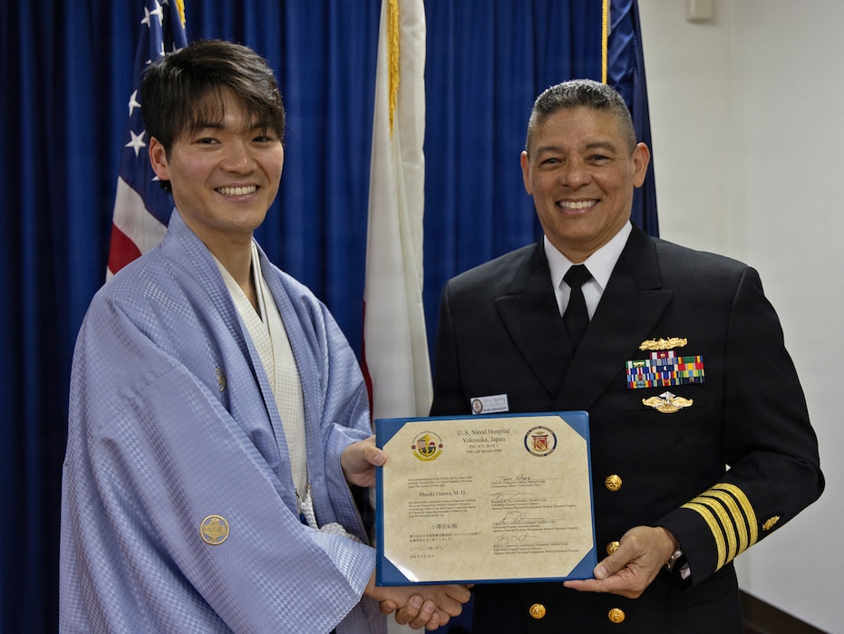 YOKOSUKA, Japan (March 20, 2026) — Capt. Donavon YapShing, deputy director of U.S. Naval Hospital Yokosuka, presents a diploma to Dr. Masaki Ozawa during the Japanese National Physician Postgraduate Education Program graduation ceremony. U.S. Naval Hospital Yokosuka graduated six physicians from the yearlong program, strengthening bilateral medical readiness and patient care across the Indo-Pacific. (U.S. Navy photo by Daniel Taylor/USNMRTC Yokosuka Public Affairs)