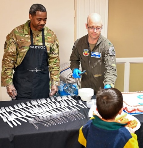Two men serving cake to boy at dinner