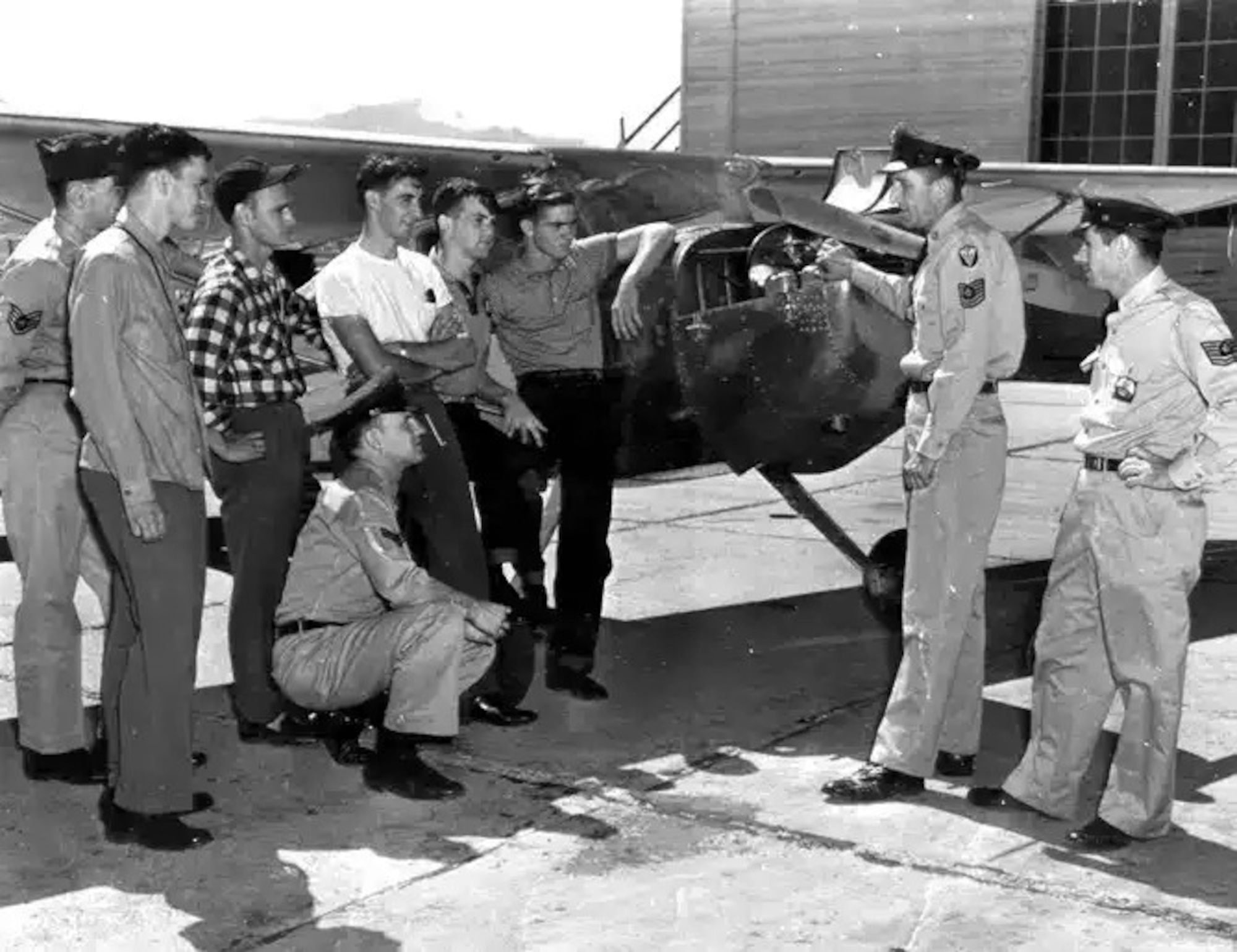 A group of men stand around a 1940s aircraft.