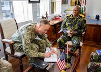 Adm. George Wikoff signs the guest book of General Charles Kahariri at the Defence Headquarters in Nairobi.