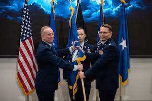 Brig. Gen. Jason Bartolomei, left, commander of the Air Force Research Laboratory, passes command of AFRL’s 711th Human Performance Wing to Col. Dale Harrell, right, while Master Sgt. Justin Knowles, first sergeant for the Wing, stands center during a change of command ceremony at Wright-Patterson Air Force Base, Ohio, March 30, 2026.