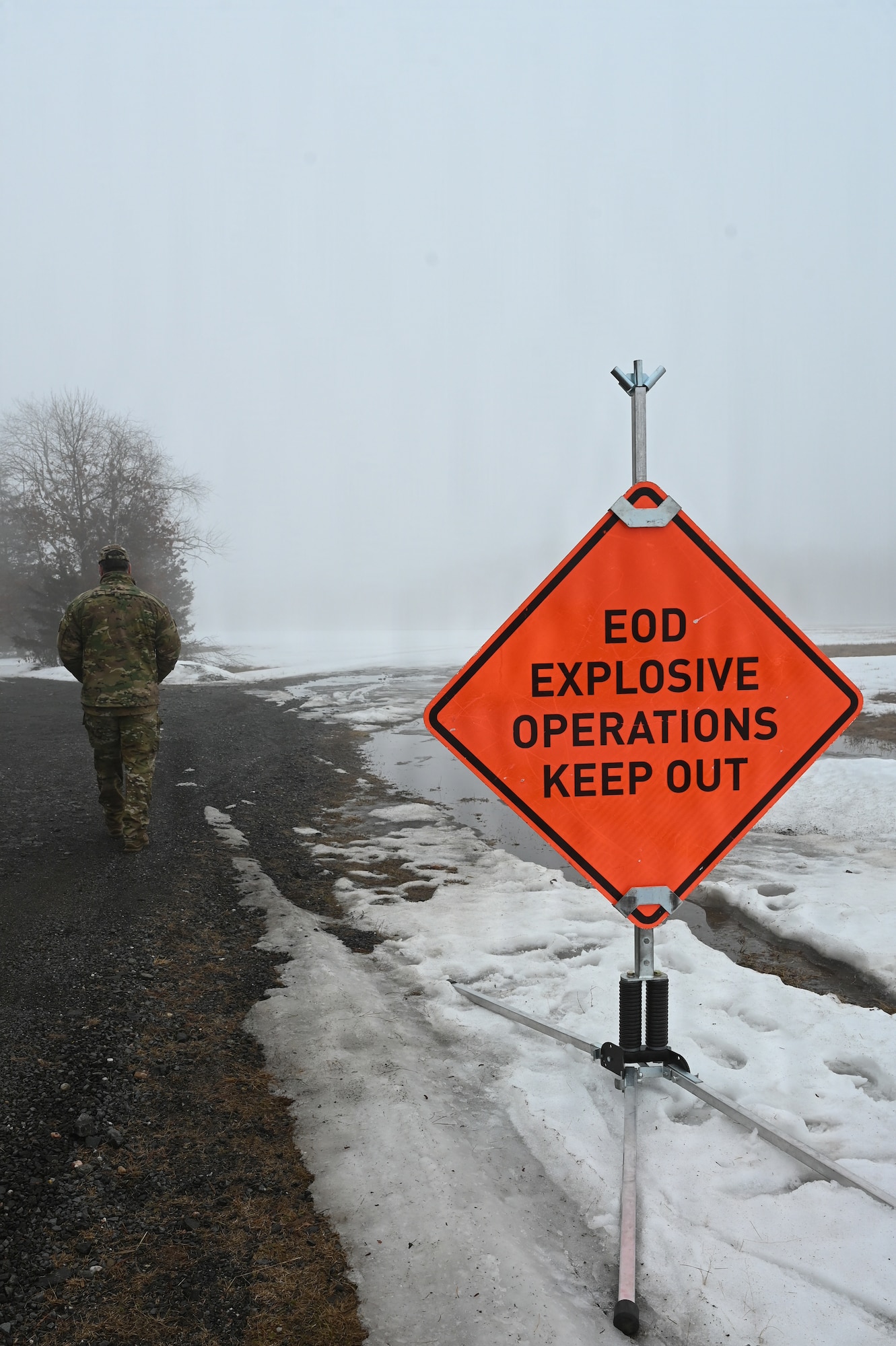 An EOD Airman walks past warning sign