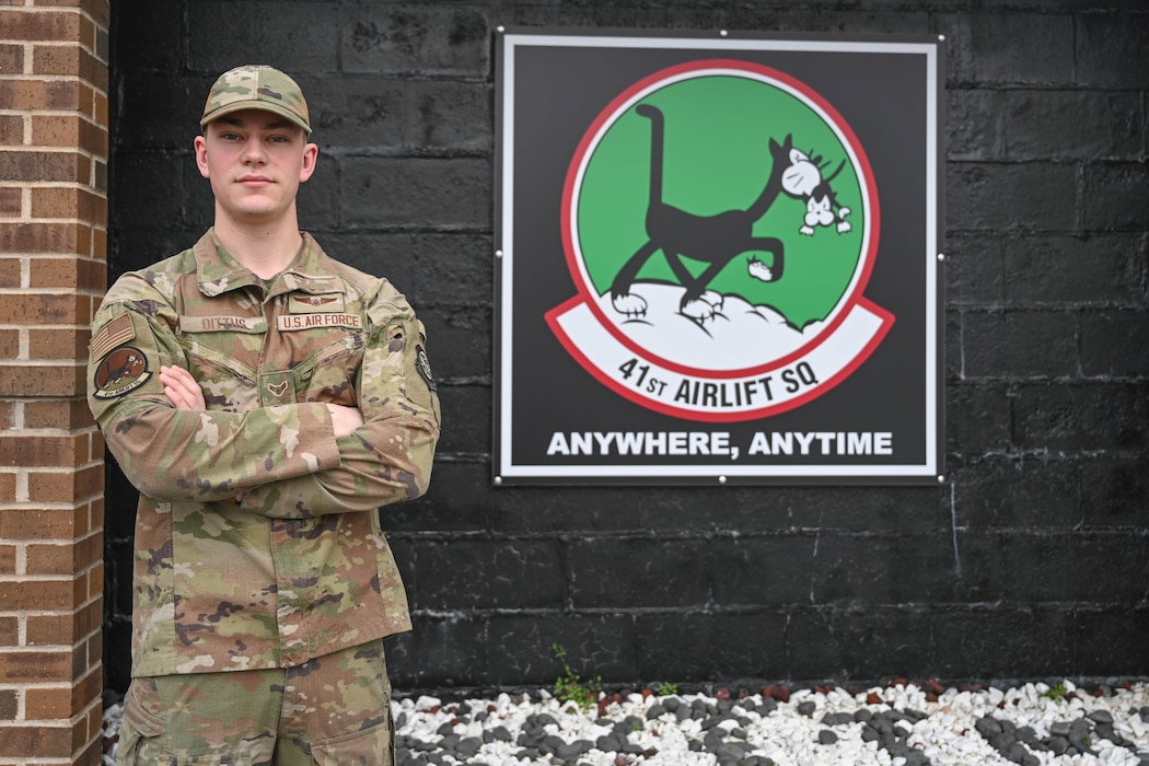 Man poses next to logo.