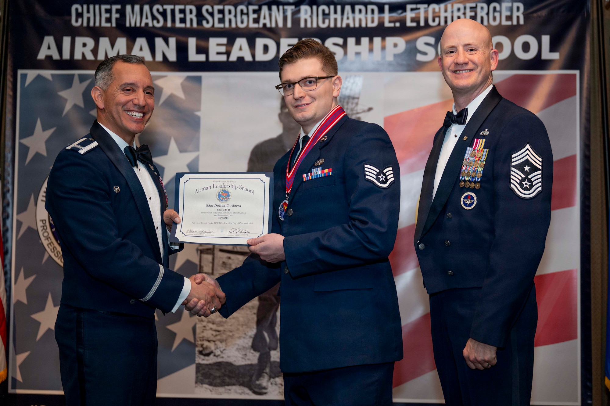 Col. Alfred Rosales, 319th Reconnaissance Wing commander, and Chief Master Sgt. William Gruenes, 319th RW command chief, presents Staff Sergeant Dalton Albers with an Airman Leadership School graduation certificate at Grand Forks Air Force Base, N.D., Feb. 12, 2026.