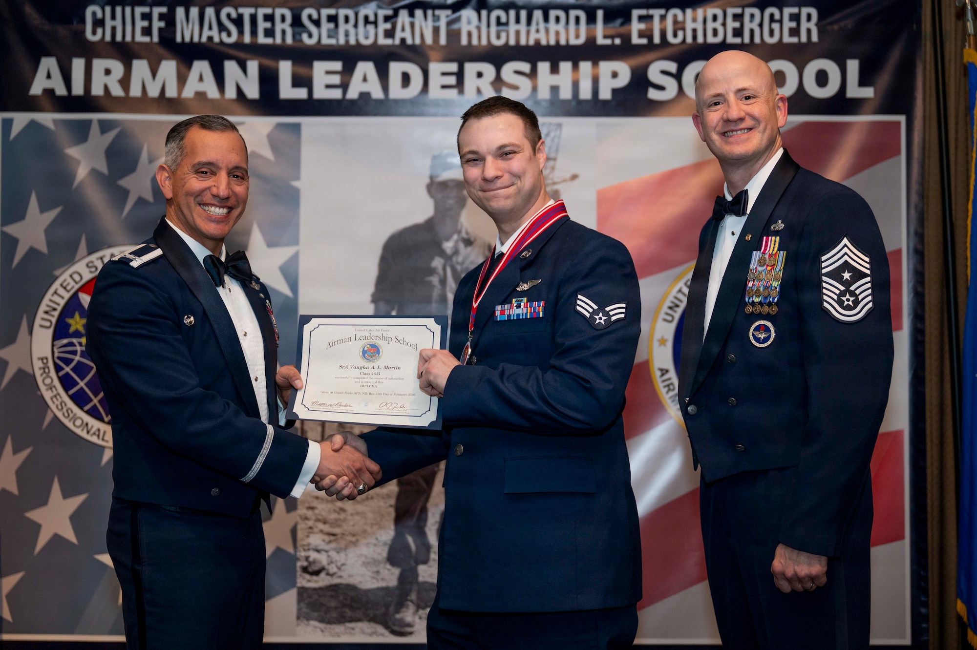 Col. Alfred Rosales, 319th Reconnaissance Wing commander, and Chief Master Sgt. William Gruenes, 319th RW command chief, presents Senior Airman Vaughn Martin with an Airman Leadership School graduation certificate at Grand Forks Air Force Base, N.D., Feb. 12, 2026.