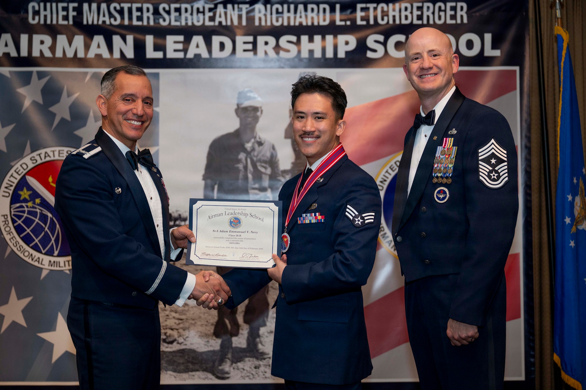 Col. Alfred Rosales, 319th Reconnaissance Wing commander, and Chief Master Sgt. William Gruenes, 319th RW command chief, presents Senior Airman Adam Emmanuel Nery with an Airman Leadership School graduation certificate at Grand Forks Air Force Base, N.D., Feb. 12, 2026.