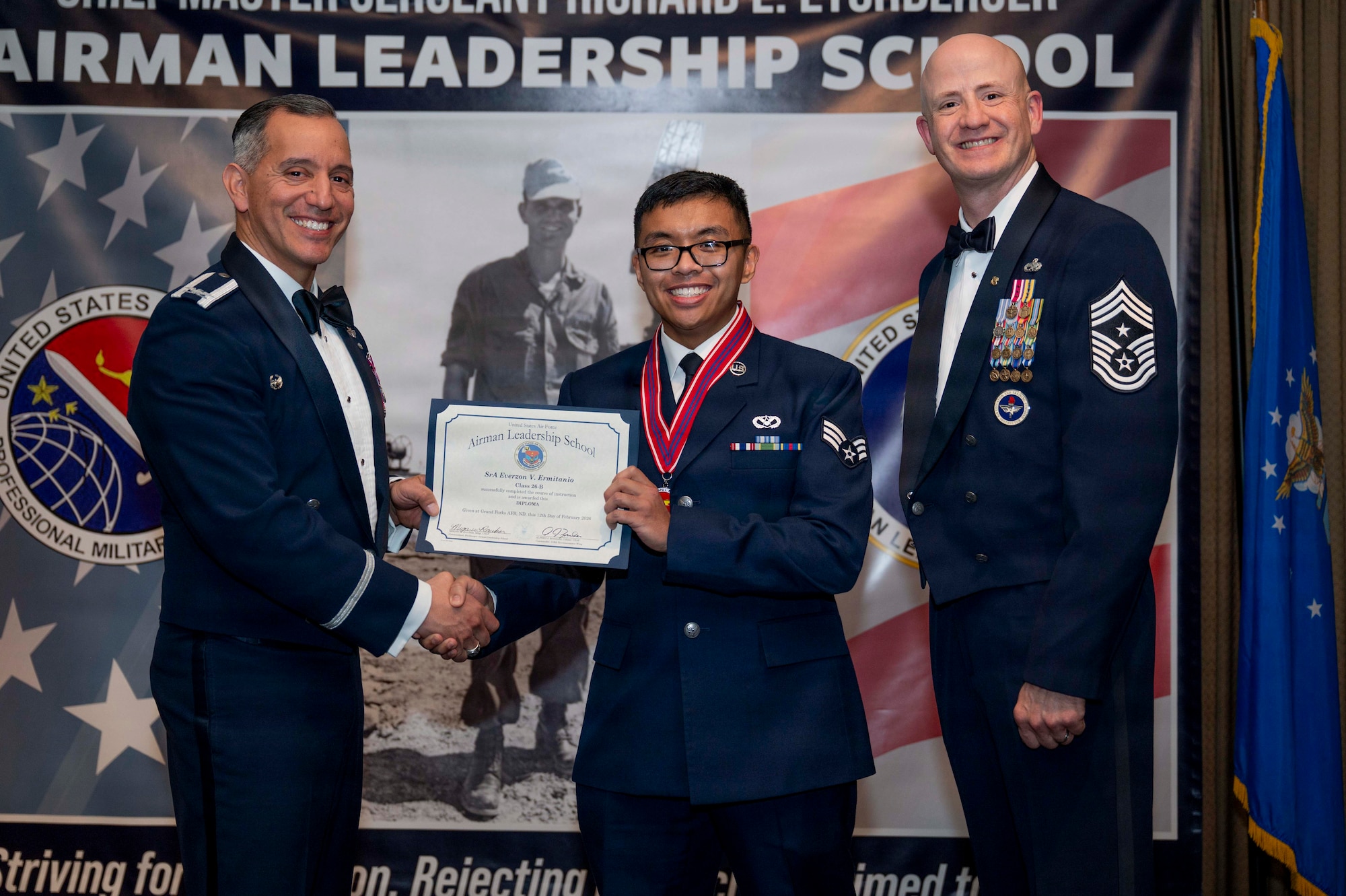 Col. Alfred Rosales, 319th Reconnaissance Wing commander, and Chief Master Sgt. William Gruenes, 319th RW command chief, presents Senior Airman Everzon Ermitanio with an Airman Leadership School graduation certificate at Grand Forks Air Force Base, N.D., Feb. 12, 2026.