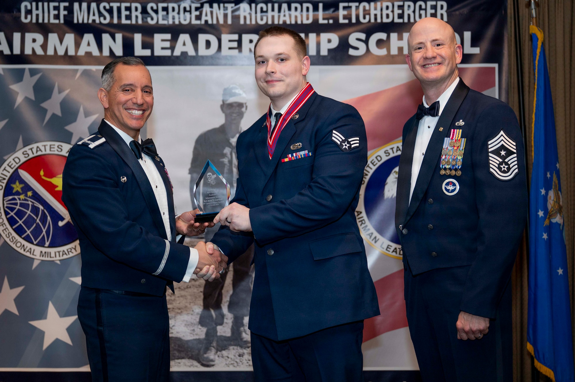 Col. Alfred Rosales, 319th Reconnaissance Wing commander, and Chief Master Sgt. William Gruenes, 319th RW command chief, presents Senior Airman Avery Crawford with an Airman Leadership School Academic Achievement Award at Grand Forks Air Force Base, N.D., Feb. 12, 2026.