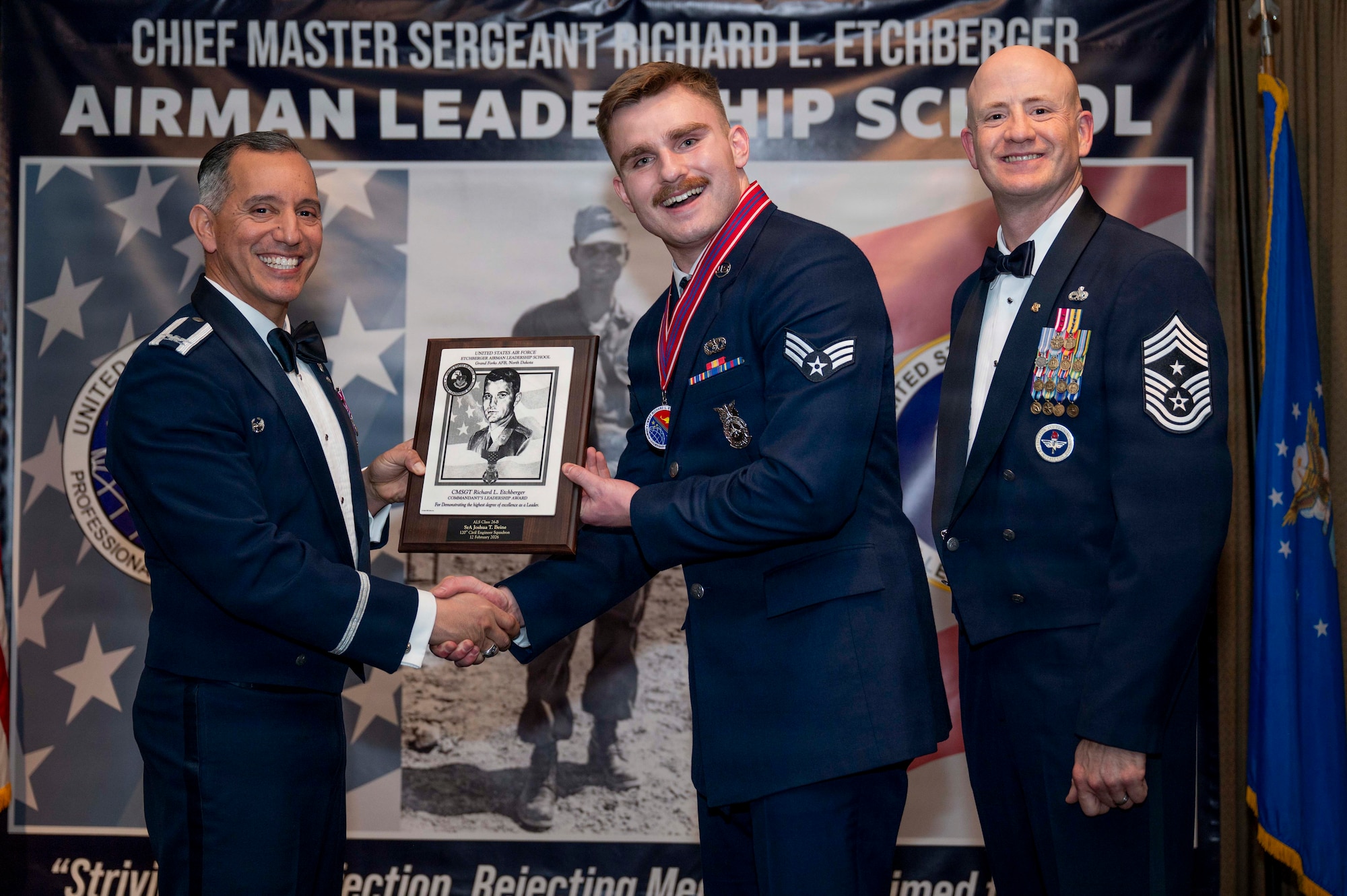 Col. Alfred Rosales, 319th Reconnaissance Wing commander, and Chief Master Sgt. William Gruenes, 319th RW command chief, presents Senior Airman Joshua Beine with an Airman Leadership School Commandant's Leadership Award at Grand Forks Air Force Base, N.D., Feb. 12, 2026.