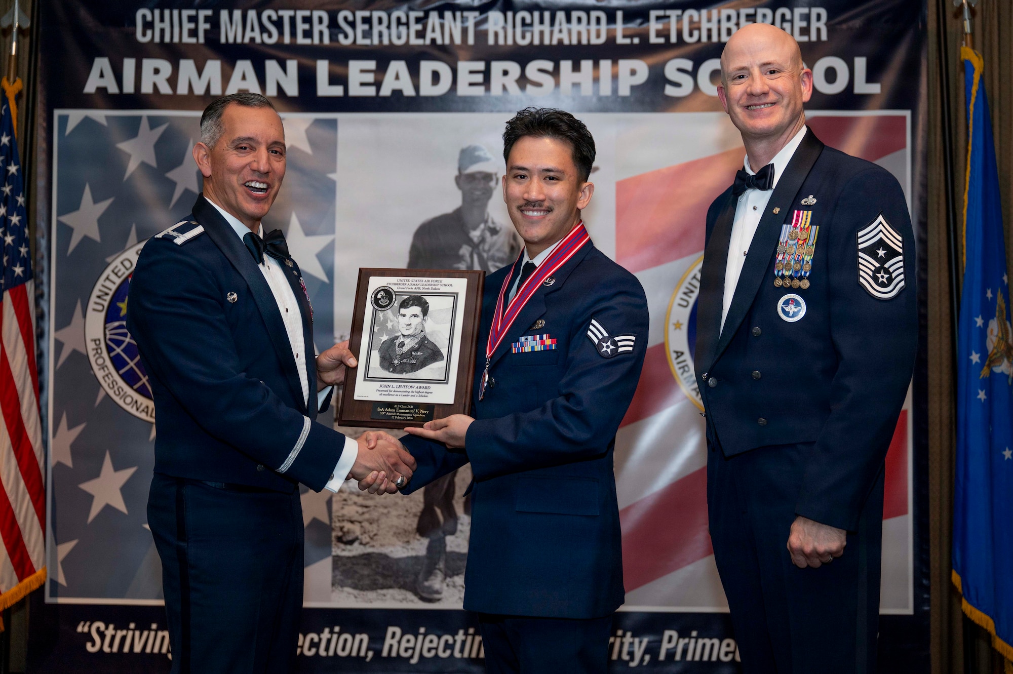 Col. Alfred Rosales, 319th Reconnaissance Wing commander, and Chief Master Sgt. William Gruenes, 319th RW command chief, presents Senior Airman Adam Emmanuel Nery with the Airman Leadership School John L. Levitow Award at Grand Forks Air Force Base, N.D., Feb. 12, 2026.