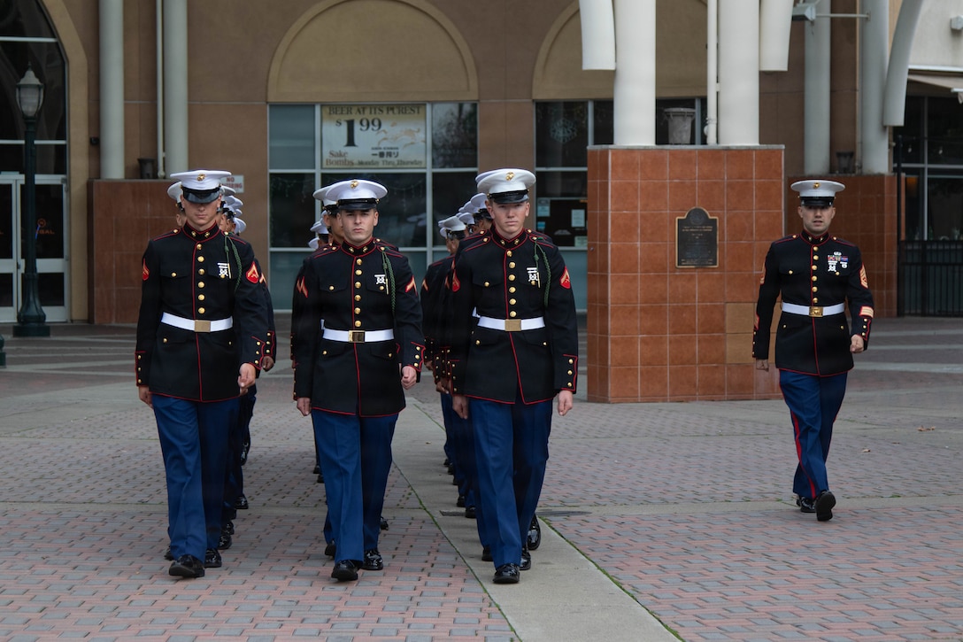 U.S. Marines with Recruiting Sub-Station Stockton, Recruiting Station Sacramento, march in formation in Downtown Stockton, California, Dec. 23, 2025. The Marines, all currently participating in the command recruiting program, paraded downtown in their dress uniforms to showcase esprit de corps to the local community. (U.S. Marine Corps photo by Staff Sgt. Ryan Harvey)