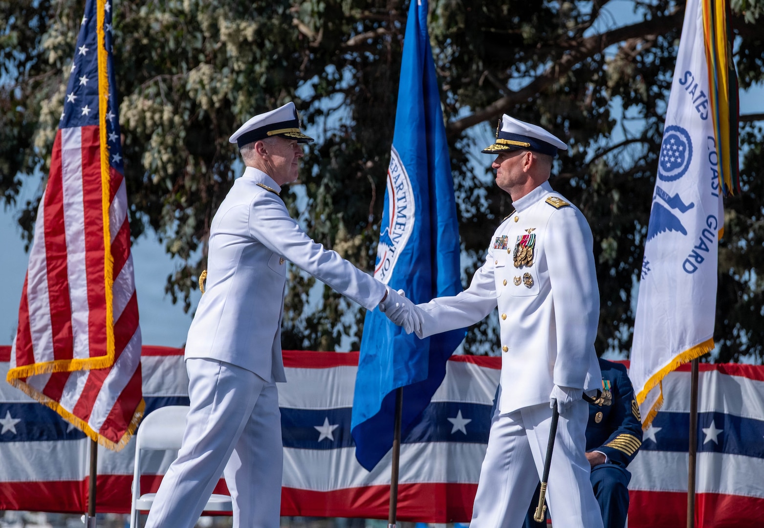 Adm. Kevin Lunday, commandant of the U.S. Coast Guard, shakes hands with Vice Adm. Joe Buzzella during an assumption of command ceremony, March 26, 2026, at Coast Guard Island, Alameda, California. The ceremony formally marked Vice Adm. Joe Buzzella as the commander of Coast Guard Pacific Area and Defense Force West. (U.S. Coast Guard photo by Petty Officer 3rd Class Charlie Valor)