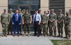 Robert Hoffman, Director for the Joint Navigation Center (JNWC), center-left, U.S. Marine Corps Gen. Christopher J. Mahoney, Vice Chairman of the Joint Chiefs of Staff, center, and U.S. Space Force Lt. Gen. Dennis Bythewood, U.S. Space Forces-Space (S4S) commander and Combined Joint Force Space Component commander, center-right, pose for a group photo in front of the JNWC with fellow leadership and staff during a distinguished visitor tour at Kirtland Air Force Base, New Mexico, March 30, 2026. During the visit, Mahoney received a series of briefings, including a JNWC capabilities brief led by Director Robert Hoffman and a Global Navigation Satellite System (GNSS) threats briefing. The JNWC provides the Department of Defense with positioning, navigation, and timing (PNT) warfighting capabilities to ensure a competitive advantage in contested environments. (U.S. Air Force photo by Airman Maurice Casilla)