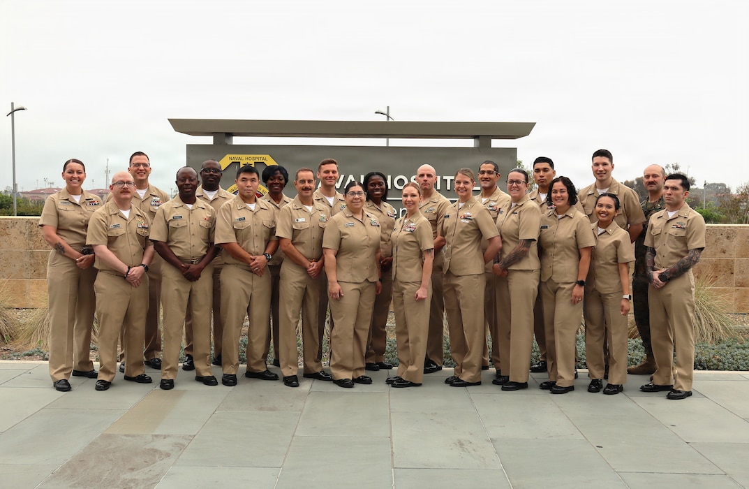 Graduates from the Division Officer Leadership Course hosted by Navy Medicine Readiness and Training Command Camp Pendleton pose with the course leaders, Cmdr. Catalina Coronado, the previous department head for NMRTC Camp Pendleton staff education and training, and Lt. Cmdr. Roberta Orozco, the current department head for NMRTC Camp Pendleton staff education and training, outside the west entrance to Naval Hospital Camp Pendleton on March 27, 2026. According to the Navy Medicine website, “DIVOLC is a service school requirement for O-1 through O-3 medical department officers who graduated from Officer Development School after January 2018.”