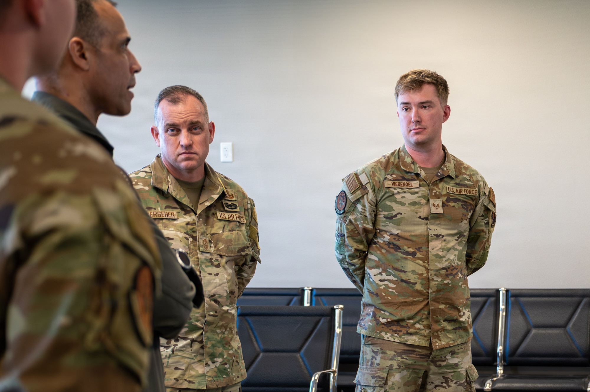 Two Airmen stand at parade rest as they look at Gen. Spain as he speaks.