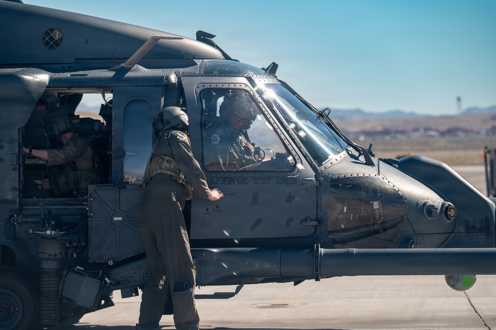 An Airman assists Gen. Adrian Spain as he gets situated in an HH-60W Jolly Green II helicopter on the helicopter pad at Nellis Air Force Base.