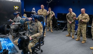 Military leadership watch as Airmen use virtual reality equipment.