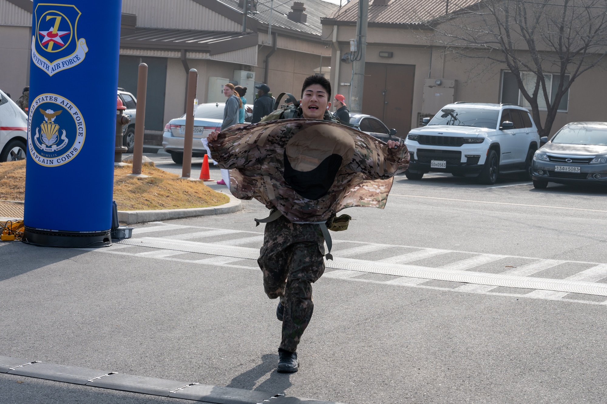 A participant crosses the finish line holding a Republic of Korea flag after completing a 30km ruck.