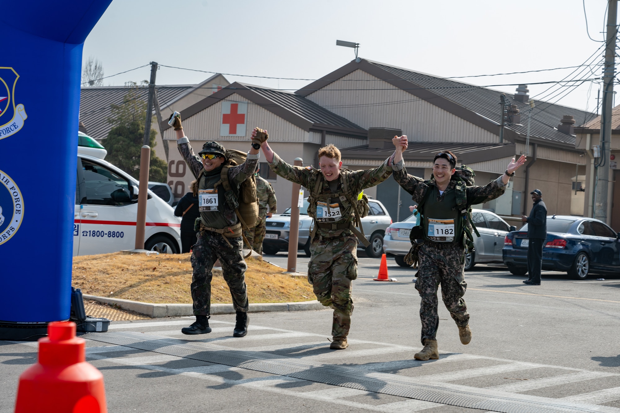 Three participants cross the finish line hand-in-hand after completing a 30km ruck.