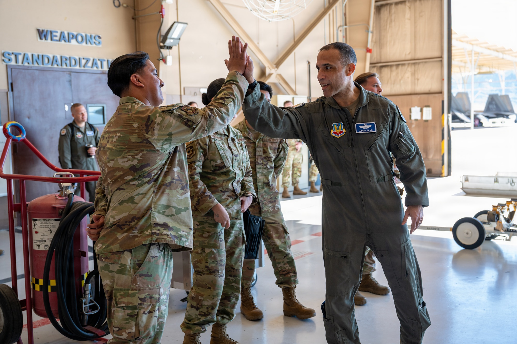 There are several Airmen lined up in a row when Gen. Spain gives a high five to the Airmen standing on the furthest left side.