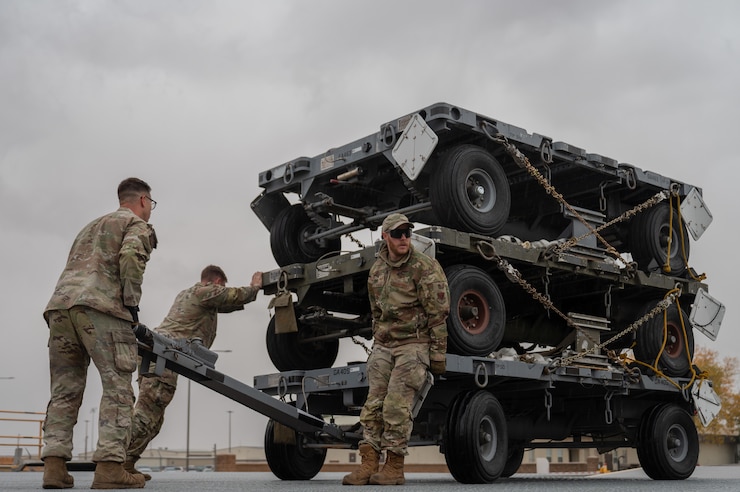 Team of Airmen transporting heavy equipment on a cart.
