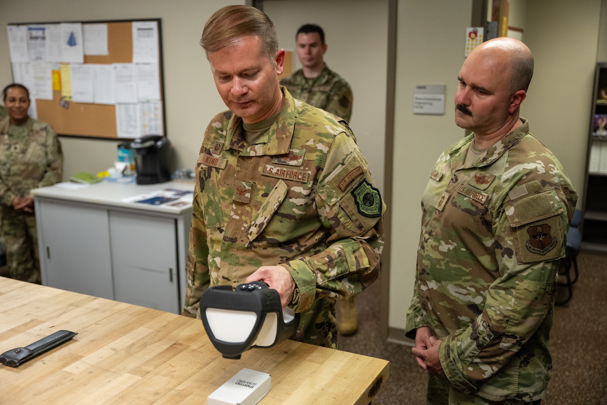 U.S. Air Force Col. Richard Kind, 97th Air Mobility Wing (AMW) commander, left, and Chief Master Sgt. Jonny Adams, 97th AMW command chief, right, measure radiation levels near a scanner at Altus Air Force Base, Oklahoma, April 13, 2026. The demonstration showed how bioenvironmental engineering Airmen monitor radiation-emitting equipment to help ensure a safe working environment across the installation. (U.S. Air Force photo by Airman 1st Class Nathan Langston)