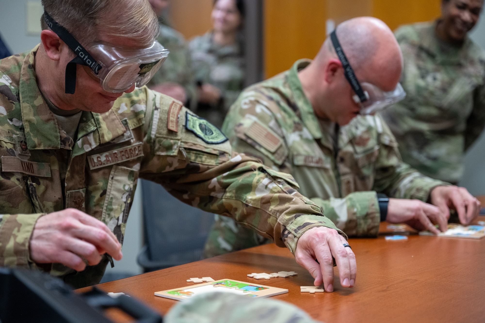 U.S. Air Force Col. Richard Kind, 97th Air Mobility Wing (AMW) commander, left, and Chief Master Sgt. Jonny Adams, 97th AMW command chief, right, put a puzzle together while wearing impairment goggles at Altus Air Force Base, Oklahoma, April 13, 2026. The goggles are designed to simulate the effects of severe alcohol impairment. (U.S. Air Force photo by Airman 1st Class Nathan Langston)