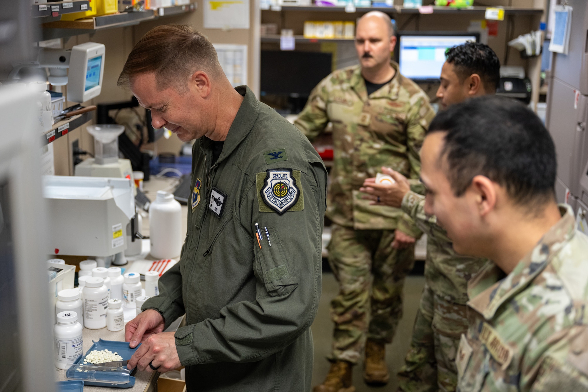 U.S. Air Force Col. Richard Kind, 97th Air Mobility Wing commander, is taught how to use a pill counter by Staff Sgt. Stephen Garcia, Altus Medical Group Healthcare Operations Squadron pharmacy technician noncommissioned officer in charge, at Altus Air Force Base, Oklahoma, April 24, 2026. The demonstration gave Kind a firsthand look at how pharmacy Airmen support patient care and medical readiness across the 97th Air Mobility Wing. (U.S. Air Force photo by Airman 1st Class Nathan Langston)