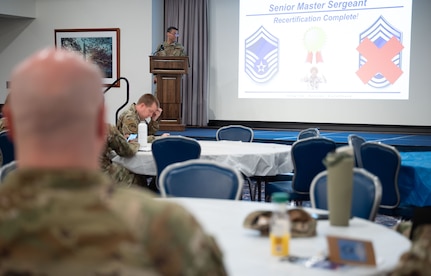 Airman sitting at table observing slideshow.
