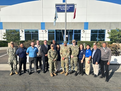 A group photo of military and civilians in front of a building.