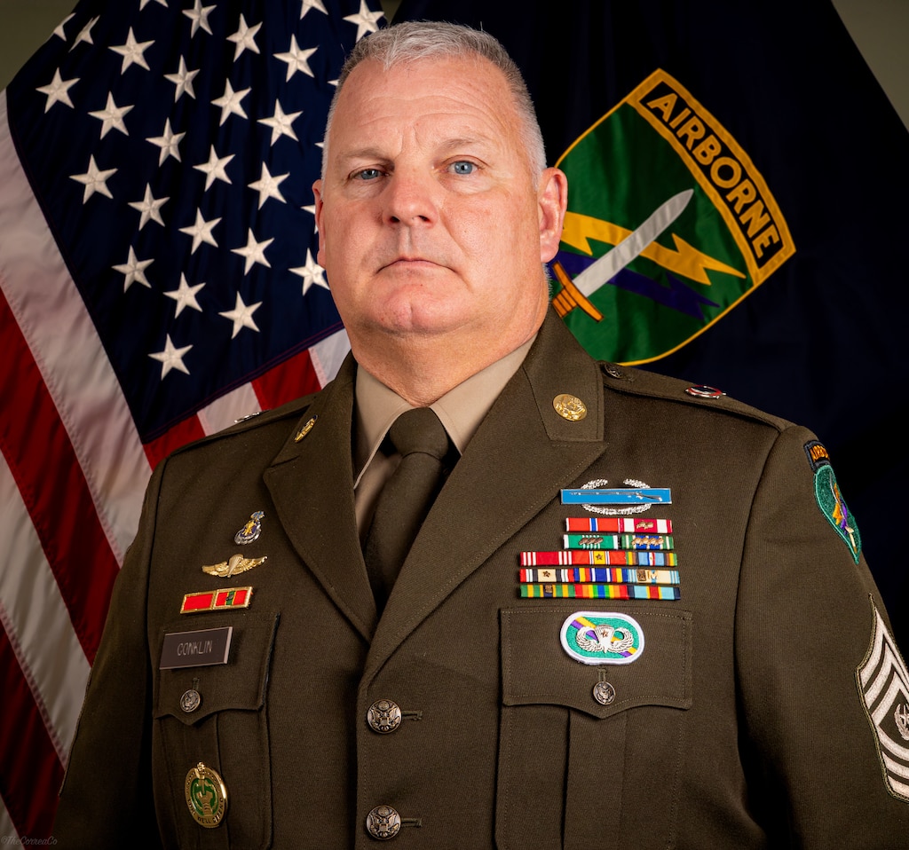 Command Sgt. Maj. George H. Conklin poses in front of the American and US Army Civil Affairs and Psychological Operations Command (Airborne) flags for his command photo.