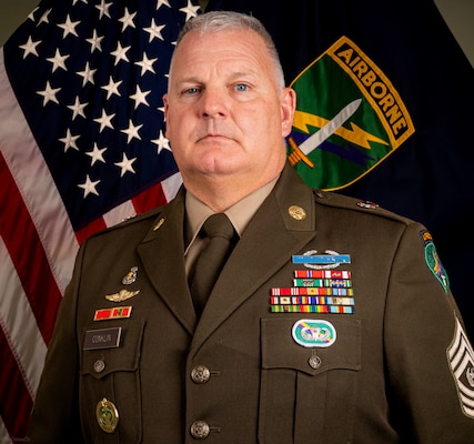Command Sgt. Maj. George H. Conklin poses in front of the American and US Army Civil Affairs and Psychological Operations Command (Airborne) flags for his command photo.