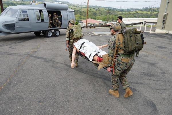 Hospital Corpsman 3rd Class Carlos Rodriguez (left), and Hospital Corpsman 3rd Class Robert Taylor (right), assigned to 1st Light Armored Reconnaissance Battalion, 1st Marine Division at Camp Pendleton, California, transport a simulated casualty from Role 1 care to Lt. Cmdr. Nicholas Stein (back left), critical care nurse, and Hospital Corpsman 1st Class Jaclyn Pickett (back right), paramedic, assigned to En-route Care System (ERCS) 56, Navy Reserve Component, Camp Pendleton, California, during a training at the Naval Expeditionary Medicine Warfighter Development Center, March 17-26, 2026. The scenario reinforced casualty evacuation and patient handoff procedures across echelons of care. (U.S. Navy photo by Petty Officer 1st Class Trevin Perry)