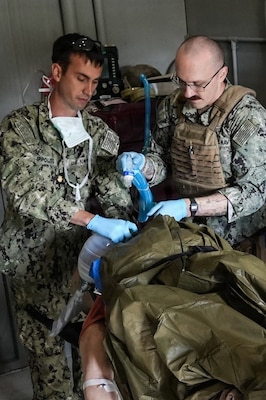Lt. Cmdr. Randall Ippolito (left), certified registered nurse anesthetist, and Hospital Corpsman 2nd Class Zachary Spears (right), respiratory therapist, both assigned to Expeditionary Resuscitative Surgical System (ERSS) 12, Navy Medicine Readiness and Training Command Camp Lejeune, North Carolina, ventilate a simulated casualty during an ERSS training at Naval Expeditionary Medicine Warfighter Development Center, Camp Pendleton, California, March 17-26, 2026. Sailors practiced airway management and casualty stabilization in a simulated austere environment to enhance readiness for deployed medical operations. (U.S. Navy photo by Petty Officer 1st Class Trevin Perry)