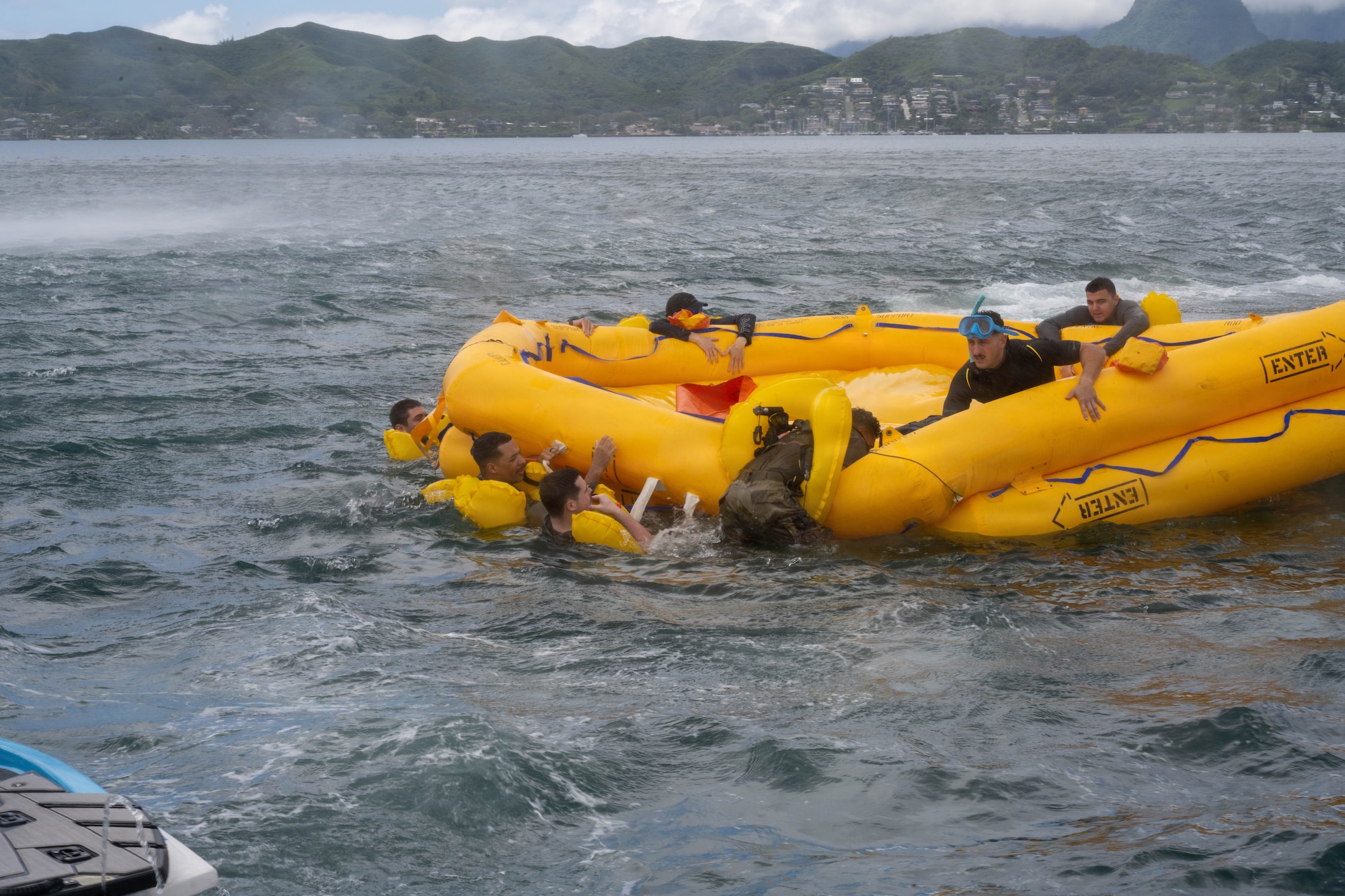 U.S. Air Force aircrew members assigned to the 535th Airlift Squadron climb into the raft during their water survival training.