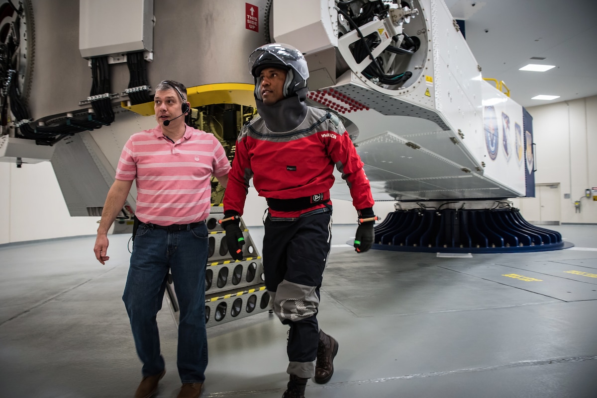 Brent Ochs, left, Air Force Research Laboratory technician, assists NASA astronaut Victor Glover, right, as he leaves the 711th Human Performance Wing’s centrifuge at Wright-Patterson Air Force Base, Ohio, Feb. 25, 2019.