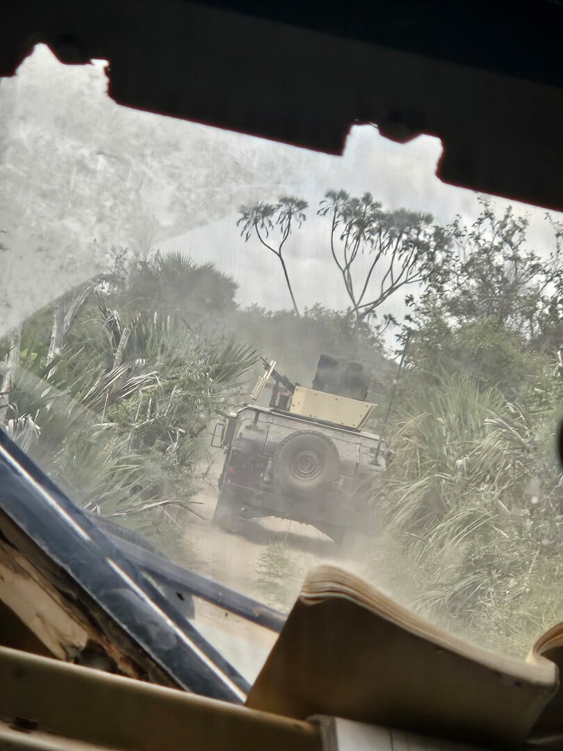 A photo of a a convoy of U.S. Army Soldiers escorting U.S. Air Force Master Sgt. Kelly Burton through a Kenyan Jungle.