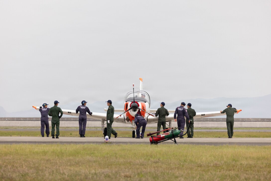 Japan Maritime Self-Defense Force members with Air Training Squadron 201, inspect a T-5 aircraft after an event during Family Day at Marine Corps Air Station Iwakuni, Japan, May 2, 2026. MCAS Iwakuni’s Family Day gave U.S. and Japanese community members, their families, local orphanages, and individuals with special needs an opportunity to experience a smaller-scale Friendship Day during the air show rehearsal, highlighting the enduring strength of the U.S.-Japan Alliance. (U.S. Marine Corps photo by Lance Cpl. Gage Collins)