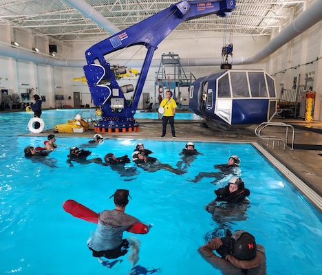 U.S. Naval Academy midshipmen participate in water survival training under the guidance of Naval Aircrewman (Mechanical) 1st Class Nicolai Villones at the Navy Aviation Survival Training Center (ASTC) Patuxent River. Supported by the expertise of Medical Service Corps (MSC) aerospace physiologists like Lt. Cmdr. Hadley Sulpizio, the ASTC's specialized team of survival instructors and medical staff ensures strict safety protocols are maintained during rigorous evolutions like underwater egress and parachute drags. ASTC Patuxent River provides CNO-mandated survival and physiological training for over 2,500 joint warfighters annually, ensuring future naval officers and test aircrews are prepared to operate safely in extreme environments.