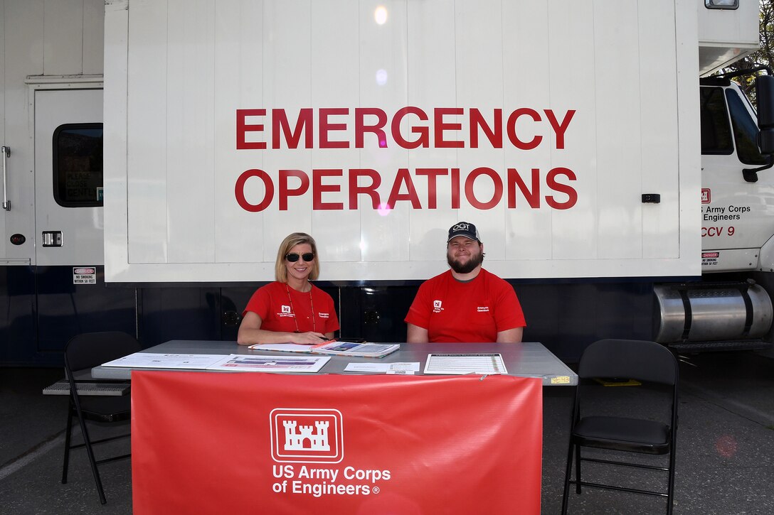 Grayson Gregory, right, a Park Ranger with Fort Worth District, and Melanie Ellis, a Strategic Communications and Outreach Project Manager, Mega Projects Division, with the Los Angeles District, staff a table outside of a U.S. Army Corps of Engineers DTOS – or Deployable Tactical Operations System, in Altadena, California, on Feb. 24, 2025. Also known as a mobile information center, the DTOS team works to provide information and guidance to those affected by the Los Angeles wildfires.