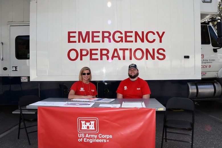 Grayson Gregory, right, a Park Ranger with Fort Worth District, and Melanie Ellis, a Strategic Communications and Outreach Project Manager, Mega Projects Division, with the Los Angeles District, staff a table outside of a U.S. Army Corps of Engineers DTOS – or Deployable Tactical Operations System, in Altadena, California, on Feb. 24, 2025. Also known as a mobile information center, the DTOS team works to provide information and guidance to those affected by the Los Angeles wildfires.