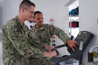 260215-N-FT324-7306. ROTA, Spain (February 15, 2026). Hospital Corpsman 3rd Class Joseph Barron, a native of Midland, Texas, assigned to Navy Medicine Readiness and Training Command Rota, works with a Sailor on a stationary exercise bike to improve strength, endurance and functional mobility during a rehabilitation session in the physical therapy clinic. Barron serves as a physical therapy technician, helping active duty service members, their families and local nationals return to full functional ability and operational readiness. (U.S. Navy photo by Lt. Cmdr. Alicia Sacks)
