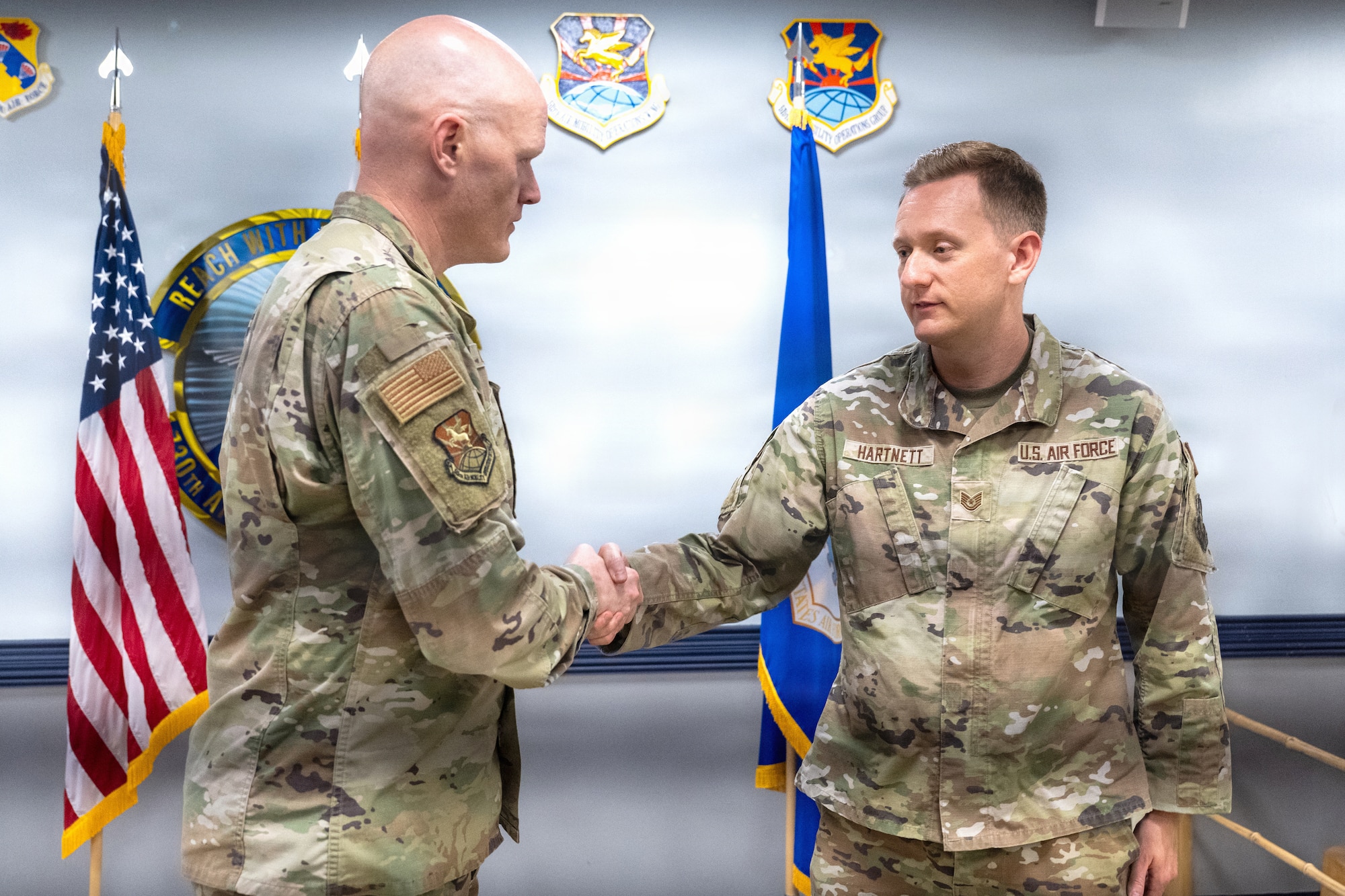 U.S. Air Force Col. Jens Lyndrup, 515th Air Mobility Operations Wing commander, coins Tech. Sgt. Scott Hartnett, 730th Air Mobility Squadron, heavy aircraft integrated avionics craftsman, in recognition of his actions during an off-duty emergency in Okinawa, Japan, at Yokota Air Base, Japan, April 27, 2026. Hartnett and four fellow Airmen applied Tactical Combat Casualty Care training to assist an injured local man after he collapsed at Ikei Beach on March 22, 2026, helping provide lifesaving care until emergency responders arrived. (U.S. Air Force photo by Staff Sgt. Shelby Rapert)
