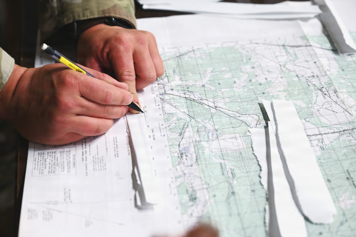 A chaplain determines distance on a map during land navigation training