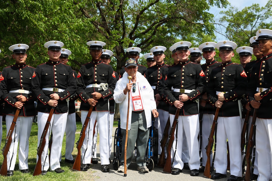 U.S. Marines with the United States Marine Corps Silent Drill Platoon, Alpha Company, Marine Barracks Washington, pose for a photo with World War II veteran Ray Hosmer following a performance at the United States Marine Corps War Memorial in Arlington, Virginia, April 15, 2026. Honor Flights bring veterans to the nation’s capital to visit memorials dedicated to their service. By honoring those who served before them, Marines reinforce the legacy and values of the Corps. (U.S. Marine Corps photo by Cpl. Brynn L. Bouchard)