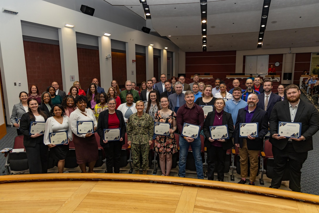 Mentors and mentees pose for a photo with DLA Weapons Support (Columbus) Commander Navy Rear Adm. Julie Treanor after the 2025-2026 Mentoring Program graduation ceremony April 17.  The ceremony, held in the agency's Operations Center Auditorium, celebrated  the dedication and resilience of 33 mentees and 33 mentors. (Photo by Andrew Young/DSCC)